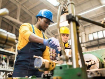 Workers operating machinery in a vocational workshop