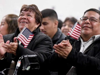 Newly naturalized citizens clapping with American flags